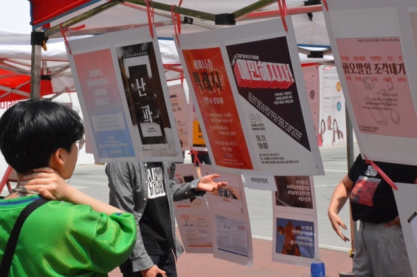 학생들이 민주광장에서 소수자·인권 운동 아카이브 전시회의 포스터를 구경하고 있다.