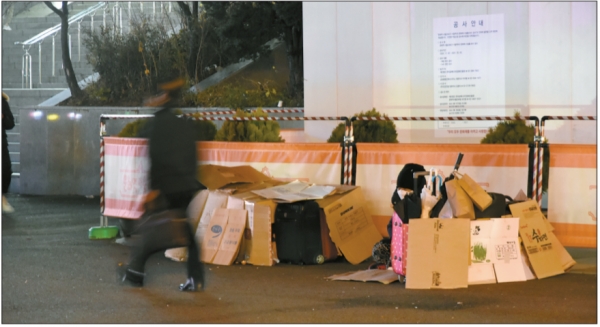 인파가 몰리는 서울역, 광장 한 구석에는 박스를 늘어놓고 생활하는 노숙인이 있다.