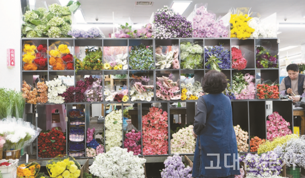 생화 꽃 도매시장에서 한 상인이 꽃을 정돈하고 있다.