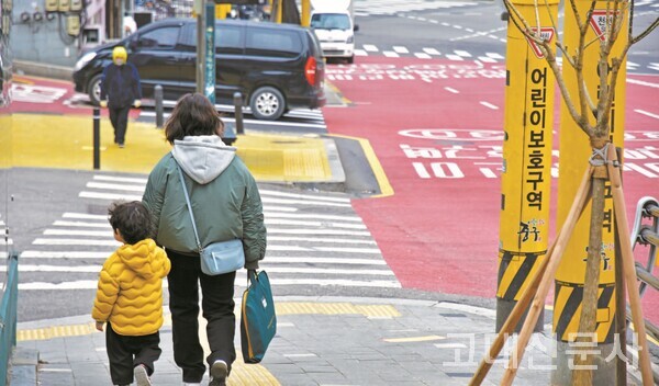 지난달 29일 서울시 중구의 어린이보호구역에서 한 어린이가 보호자와 함께 길을 걸어가고 있다.