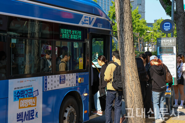 안암역3번출구 정류장에서 학생들이 273번 버스를 타고 있다.