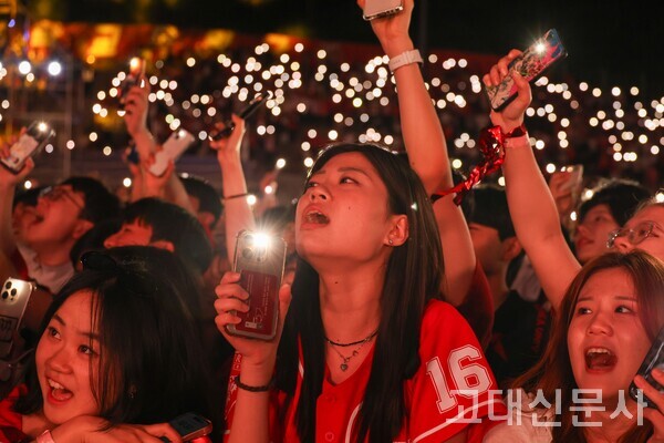 휴대폰 라이트를 켜고 공연을 감상하는 학생들의 모습.