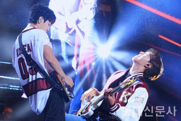 씨엔블루의 정용화와 이정신이 마주 보며 악기를 연주하고 있다.